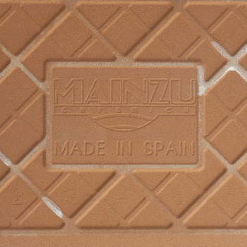 Eine Keramikfliese zeigt den geprägten Text „MAINZU ceramica“ und „MADE IN SPAIN“ sowie ein diagonales Gittermuster in Terrakott