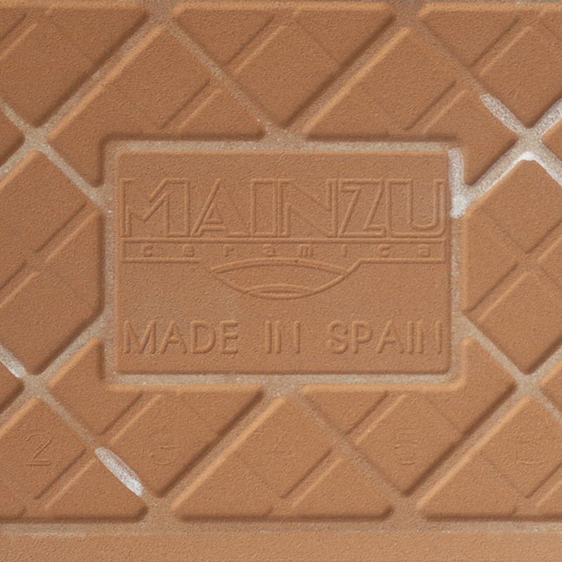 Un carreau de céramique présente les textes en relief « MAINZU ceramica » et « MADE IN SPAIN », avec un motif de grille diagonal