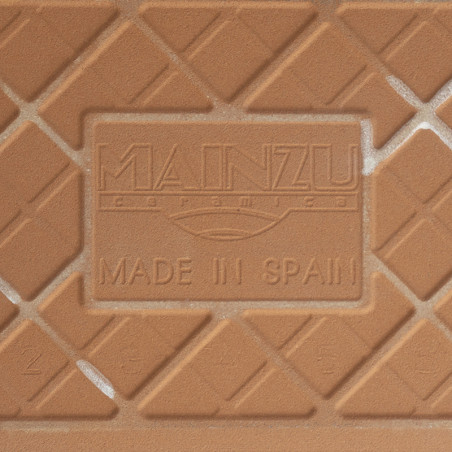 Eine Keramikfliese zeigt den geprägten Text „MAINZU ceramica“ und „MADE IN SPAIN“ sowie ein diagonales Gittermuster in Terrakott