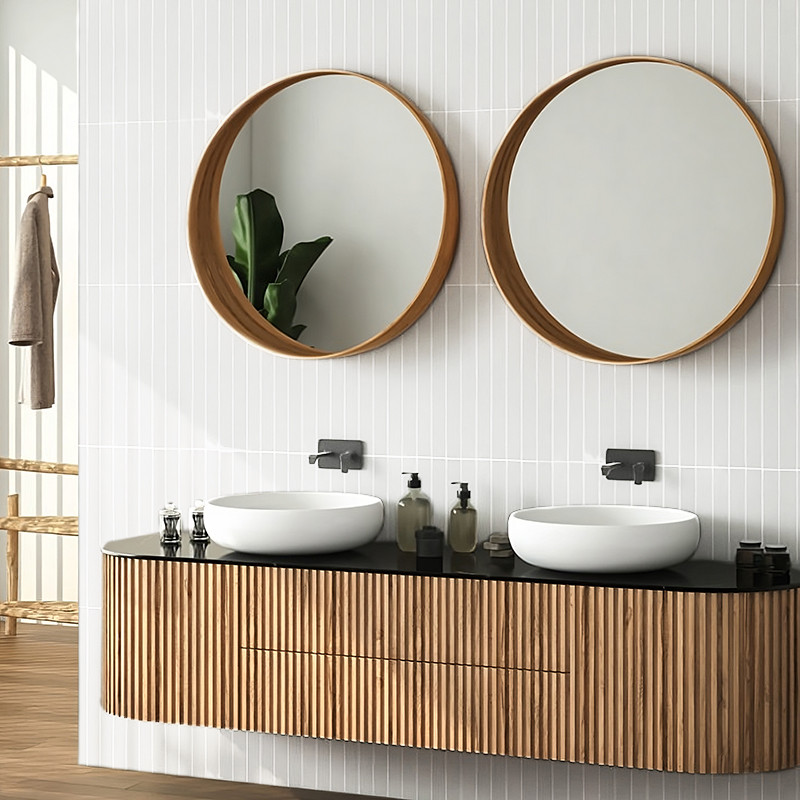 Über einem modernen Waschtisch mit Holzstruktur hängen zwei runde Spiegel, die das Licht reflektieren. Weiße Waschbecken und Sei