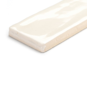 Een rechthoekige keramische tegel ligt plat en vertoont een glanzend crèmekleurig oppervlak met zachte, golvende patronen. Het r