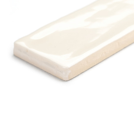 Een rechthoekige keramische tegel ligt plat en vertoont een glanzend crèmekleurig oppervlak met zachte, golvende patronen. Het r