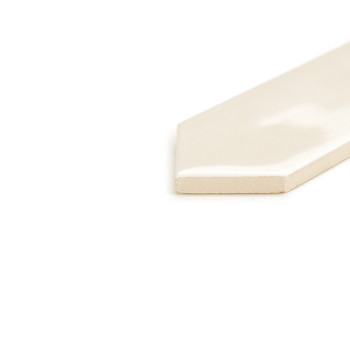 Een glanzende, gebroken witte tegel met spitse rand rust op een wit oppervlak en reflecteert het licht op subtiele wijze in een 