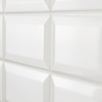 Weiße, glänzende Keramikfliesen bilden ein Gittermuster, reflektieren das Licht und sorgen für ein klares und modernes Erscheinu