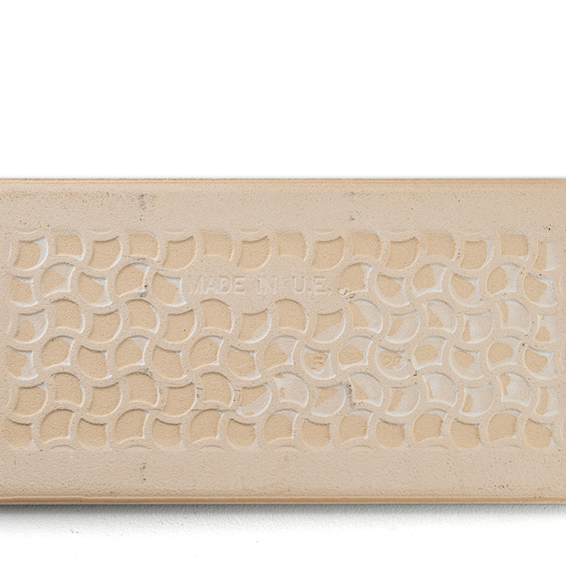 A rectangular beige tile displays a repeating pattern of interlocking semicircles. In the center, faint text reads: `MADE IN UAE