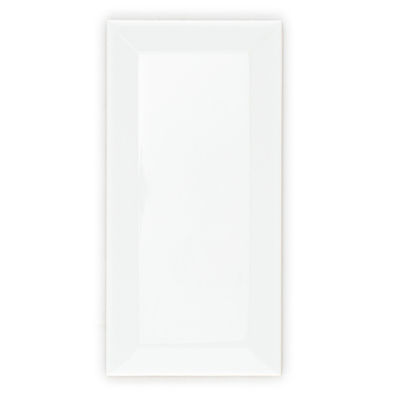 Eine glänzende, rechteckige weiße Fliese mit abgeschrägten Kanten liegt auf einem schlichten weißen Hintergrund und reflektiert 