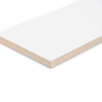 Un carreau de céramique blanche rectangulaire à la surface lisse est posé en angle, mettant en valeur ses bords beiges, sur un f