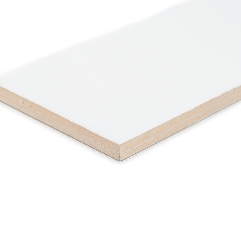 Um ladrilho cerâmico branco retangular com superfície lisa fica inclinado, destacando suas bordas bege, contra um fundo branco l