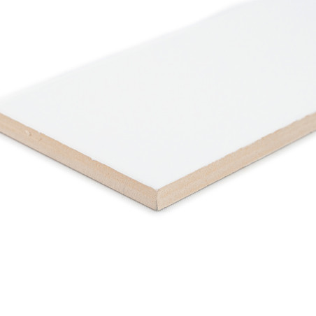 Un carreau de céramique blanche rectangulaire à la surface lisse est posé en angle, mettant en valeur ses bords beiges, sur un f