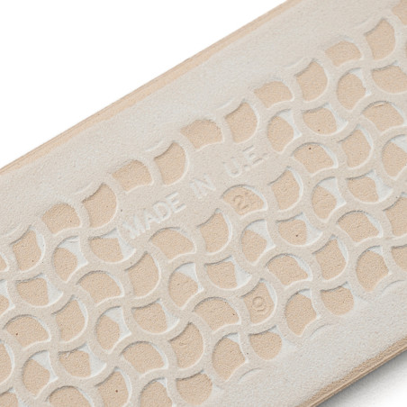 Eine beige Gummisohle weist ein erhabenes, ineinandergreifendes geometrisches Muster mit dem Text „MADE IN U.S.A.“ auf. in der M