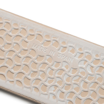 Beige textured surface embossed with overlapping semicircles displaying `MADE IN SPAIN,` suggesting craftsmanship on a shoe or a