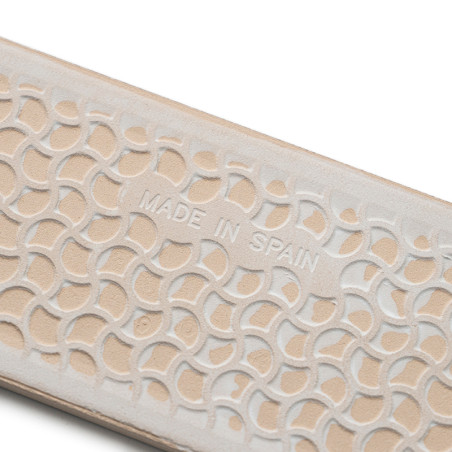 Beige textured surface embossed with overlapping semicircles displaying `MADE IN SPAIN,` suggesting craftsmanship on a shoe or a