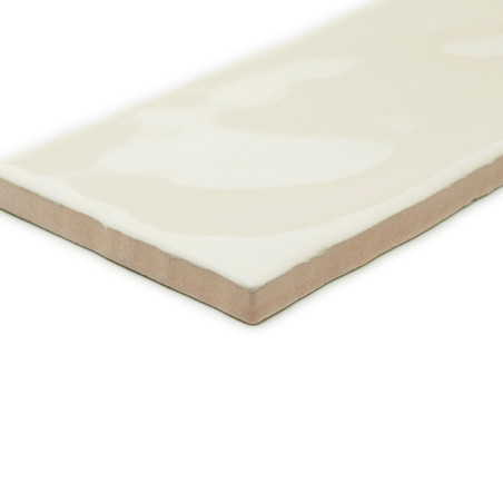 Eine rechteckige Keramikfliese mit glänzender, cremefarbener Oberfläche und abgeschrägten Kanten liegt isoliert auf einem schlic