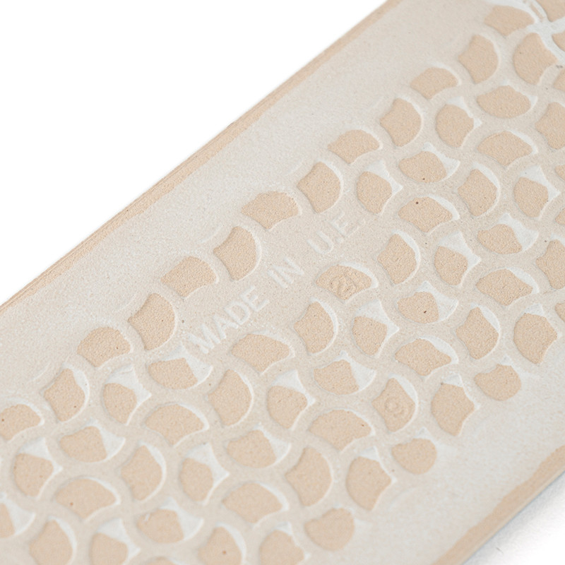 A beige, rectangular tile displays a repeating geometric pattern. `MADE IN U.E.` is embossed centrally, suggesting manufacturing