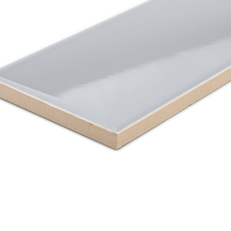 A rectangular, glossy, light grey ceramic tile with a beige edge rests isolated on a blank white background.
