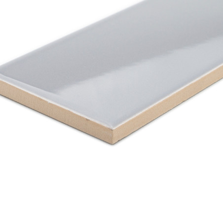 Un carreau de céramique rectangulaire, brillant et gris clair avec un bord beige est isolé sur un fond blanc vierge.