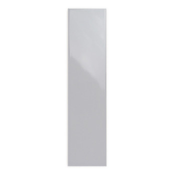 Um ladrilho retangular brilhante fica verticalmente, refletindo sutilmente a luz, colocado contra um fundo branco liso.