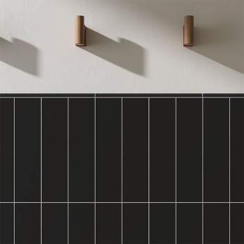 Dark rectangular tiles are arranged in a grid pattern against a smooth, light wall. Two wooden hooks cast distinct shadows above