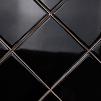 Shiny, black, diamond-shaped tiles are arranged in a neat, repeating pattern, creating a sleek and modern surface.