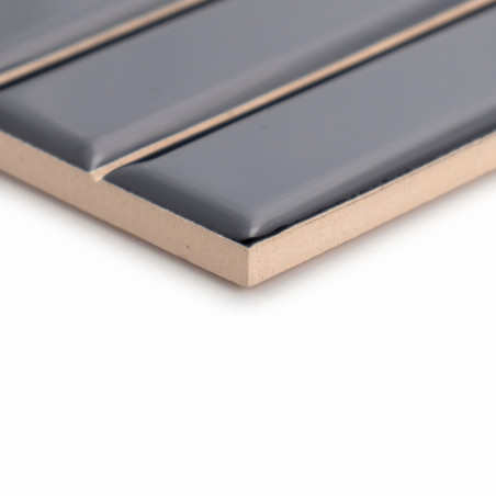 A rectangular tile with raised, glossy dark gray strips sits atop a beige surface, highlighting its sleek, modern design.
