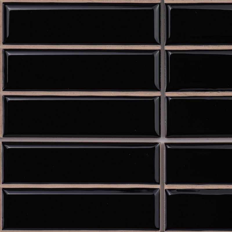 Zwarte rechthoekige tegels zijn gerangschikt in een raster, gescheiden door beige voeglijnen, waardoor een strak en glanzend opp