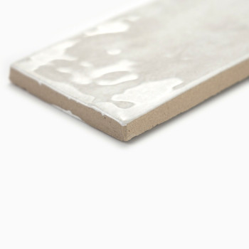 Een rechthoekige tegel ligt op een vlak oppervlak, waarbij de glanzende, witte bovenkant het licht reflecteert, in contrast met 