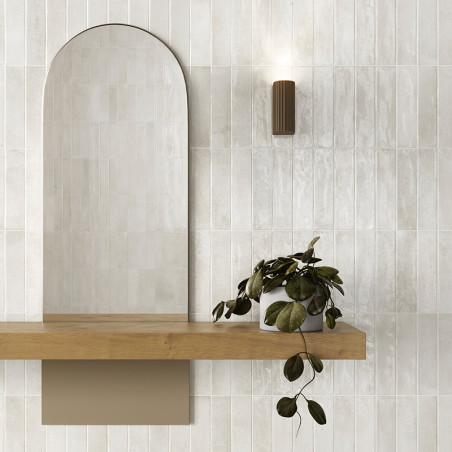 Über einem Holzregal ruht ein gewölbter Spiegel, begleitet von einer üppigen Hängepflanze. Eine moderne, zylindrische Wandleucht