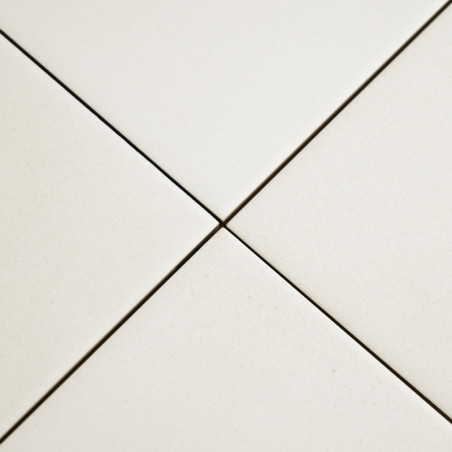 Vier weiße Keramikfliesen treffen an einem zentralen Punkt aufeinander und bilden eine Plusform mit schmalen Fugenlinien, die in