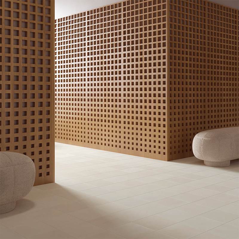 Een houten rastermuur scheidt een kamer versierd met beige vloertegels, vergezeld van ronde grijze voetenbankjes. De ruimte oogt