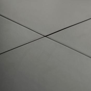 Graue Keramikfliesen überschneiden sich im rechten Winkel und bilden ein Kreuzmuster in einer glatten, gleichmäßig beleuchteten 