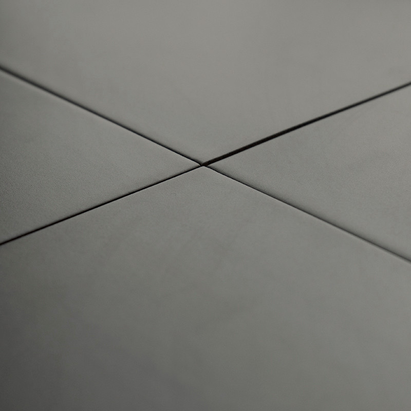 Les carreaux de céramique grises se croisent à angle droit, formant un motif en croix, dans un environnement lisse et uniforméme