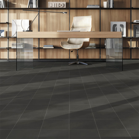 Hinter einem modernen Schreibtisch mit Glasbeinen steht ein eleganter Bürostuhl. Regale voller Bücher und Deko säumen den hölzer