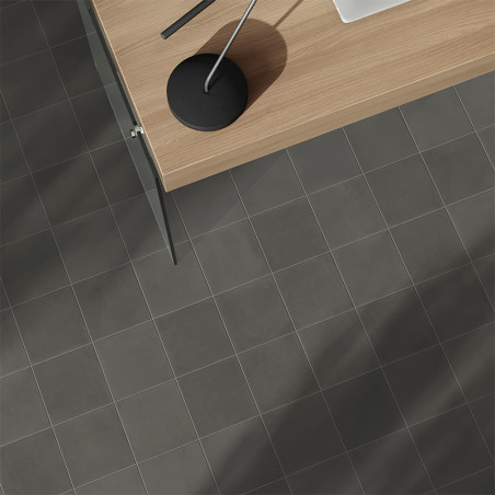 Ein grauer Fliesenboden liegt unter einem modernen Holzschreibtisch mit einer eleganten schwarzen Lampe und schafft eine minimal