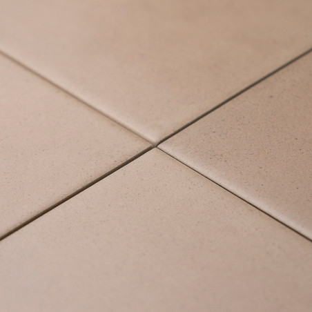 Vier beige Fliesen kreuzen sich sauber und bilden an ihren Ecken ein kleines Kreuz. Sie sind auf einer flachen, ebenen Oberfläch