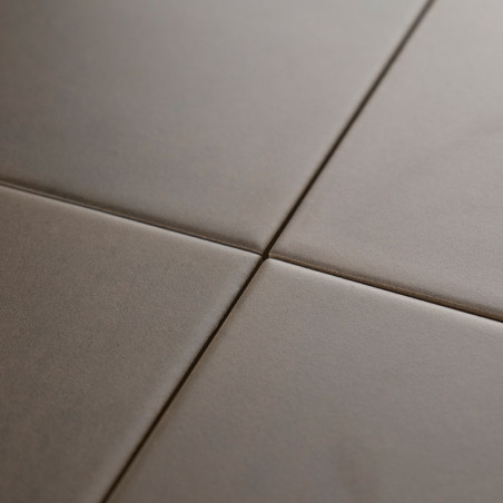 Vier glatte, matte, quadratische Fliesen treffen an einer zentralen Fugenlinie aufeinander und bilden ein minimales Gittermuster