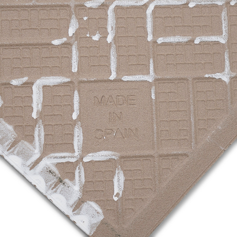 Um ladrilho cerâmico quadrado com padrão de grade bege apresenta o texto `MADE IN SPAIN` gravado em sua superfície, cercado por 
