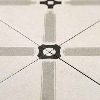 Eine Keramikfliese weist ein symmetrisches geometrisches Muster mit sich kreuzenden grauen Linien auf, die ein Kreuz bilden, in 