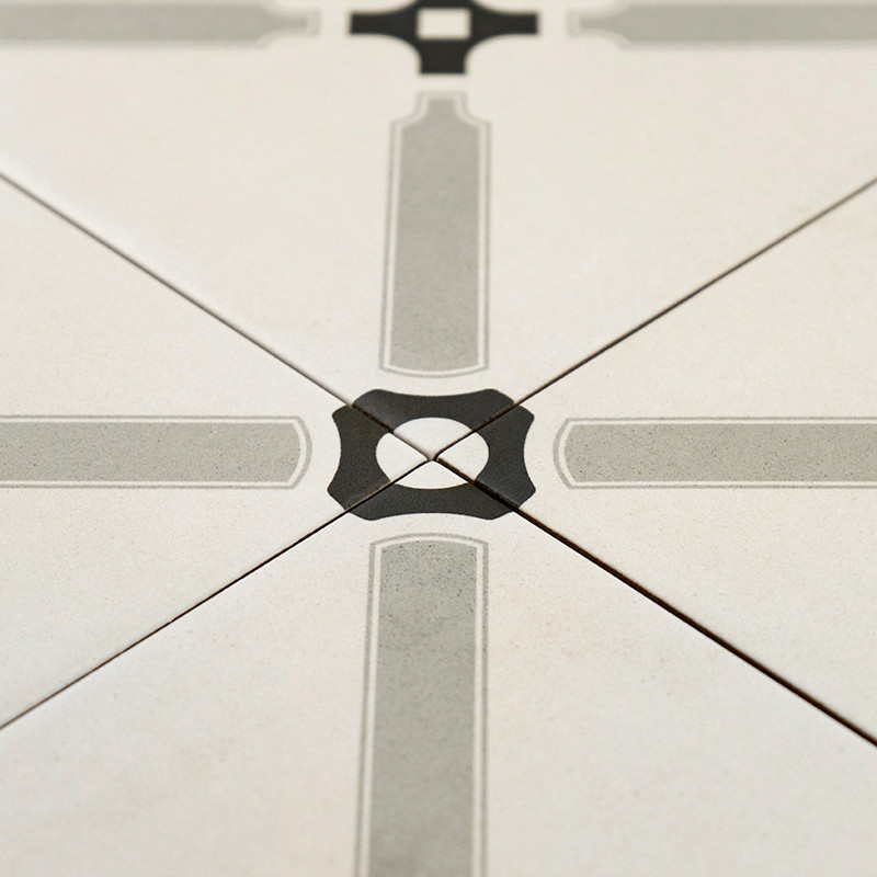 Un carreau de céramique présente un motif géométrique symétrique avec des lignes grises entrecroisées formant une croix, centrée