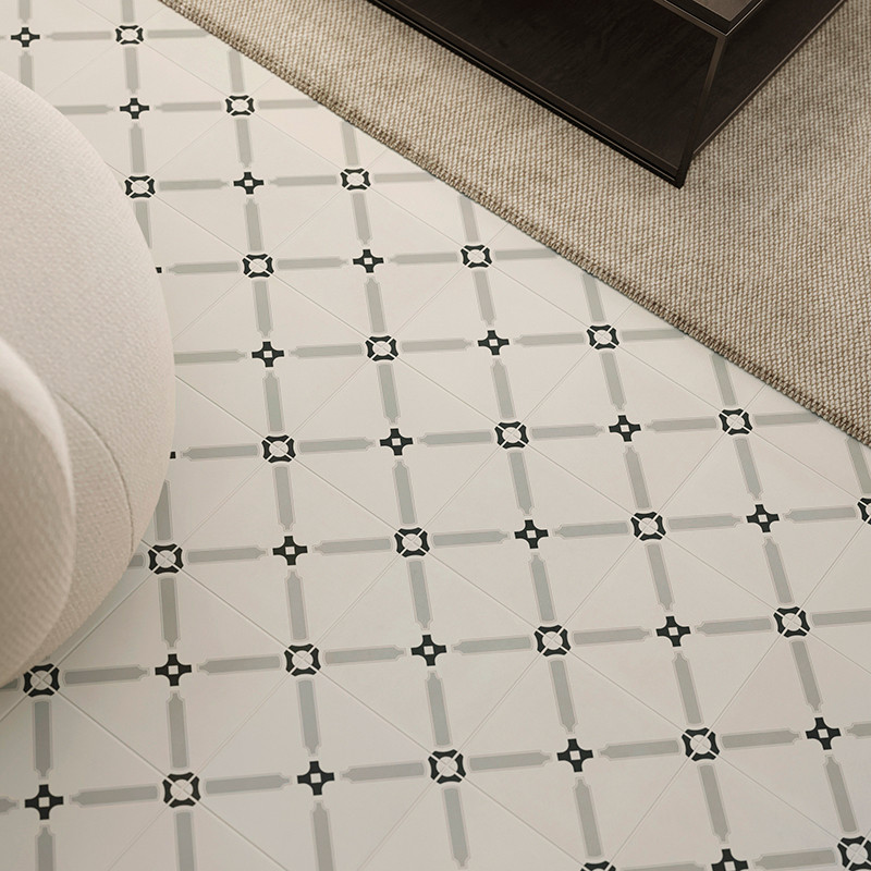 Le carrelage blanc présente un motif de petits carrés noirs reliés par des lignes grises, à côté d'un tapis beige et d'un canapé