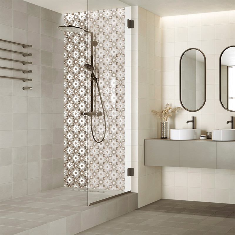 Un área de ducha con azulejos estampados cuenta con un cabezal de ducha de metal oscuro. Está en un baño moderno con dos lavabos Un área de ducha con azulejos estampados cuenta con un cabezal de ducha de metal oscuro. Está en un baño moderno con dos lavabos