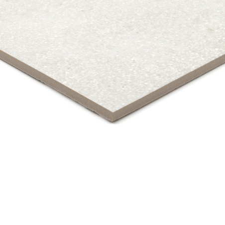 Eine rechteckige, gesprenkelte hellgraue Keramikfliese liegt auf einer weißen Oberfläche und zeigt ihr dünnes Profil und ihre gl