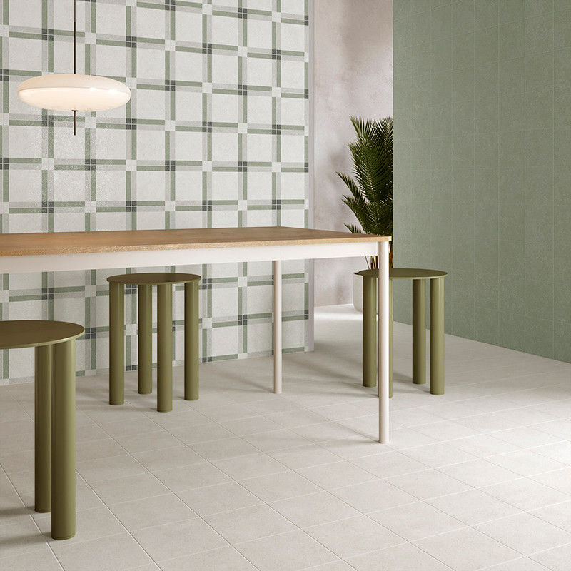 Una moderna mesa de comedor se asienta sobre azulejos cuadrados claros, rodeada de taburetes cilíndricos verdes. Una pared y una