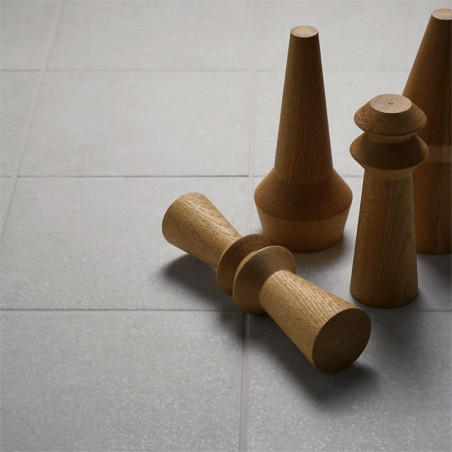 Hölzerne Schachfiguren liegen verstreut auf einer hellgrauen Fliesenfläche, eine Figur ist umgeworfen. Die Szene ist ruhig und m