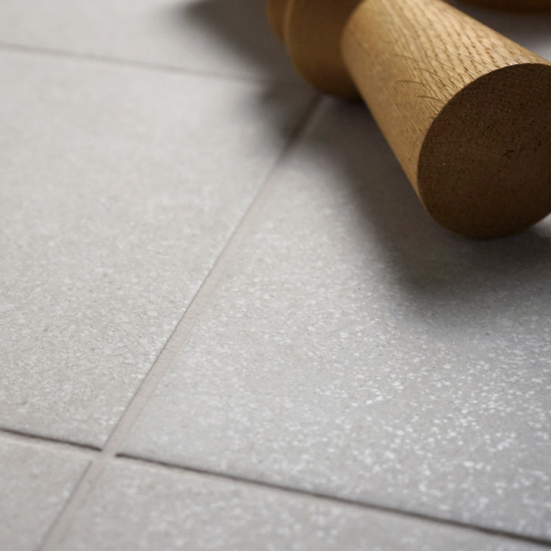 Un rodillo de madera descansa sobre una superficie lisa de azulejos de color gris claro, creando un ambiente de cocina doméstico
