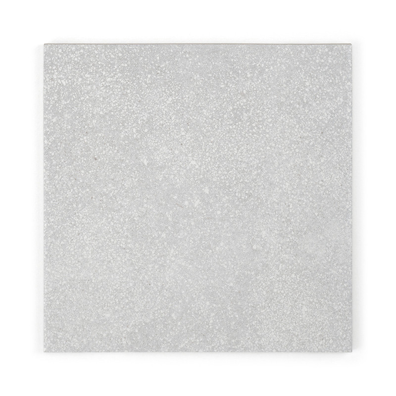 Eine quadratische, hellgraue Fliese zeigt eine strukturierte Oberfläche mit gesprenkelten Mustern vor einem schlichten weißen Hi