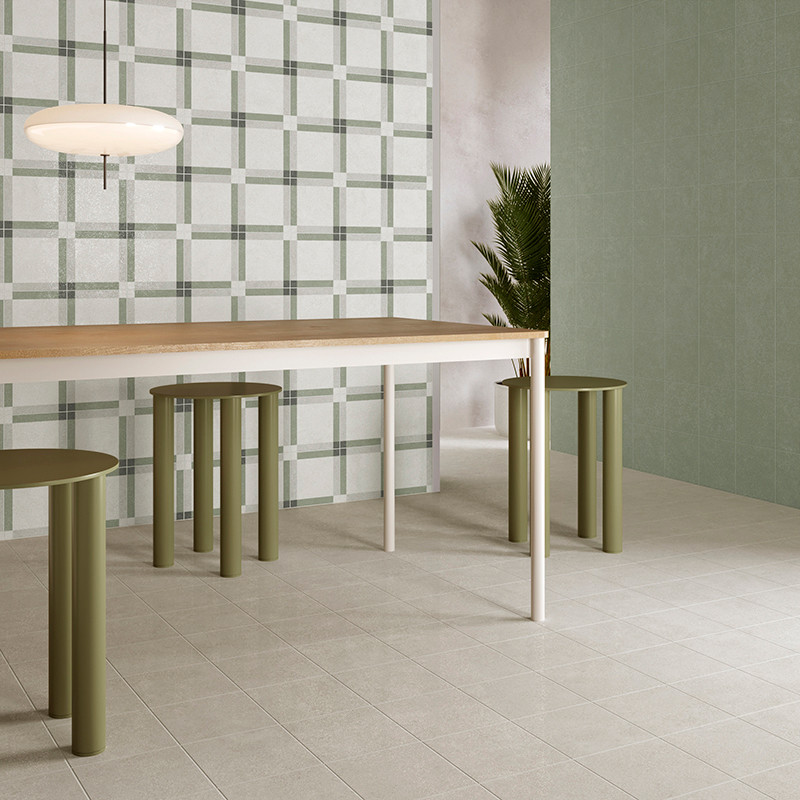 Une table à manger moderne avec des tabourets cylindriques verts se dresse sur un sol carrelé clair, entouré de carreaux muraux 