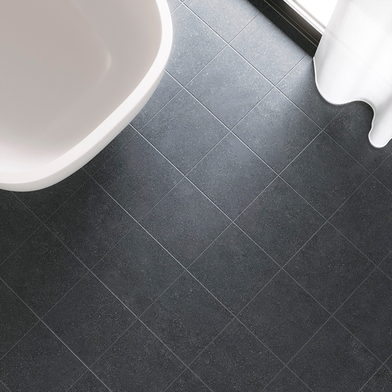 Los azulejos cuadrados de color gris oscuro forman un patrón de cuadrícula en el suelo del baño junto a una bañera blanca y una 