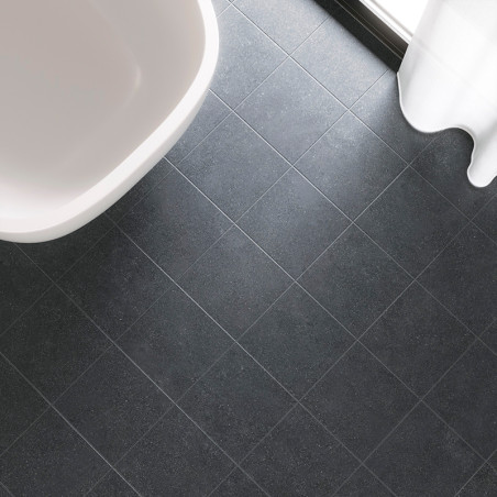 Dunkelgraue quadratische Fliesen bilden ein Gittermuster auf einem Badezimmerboden neben einer weißen Badewanne und einem transp