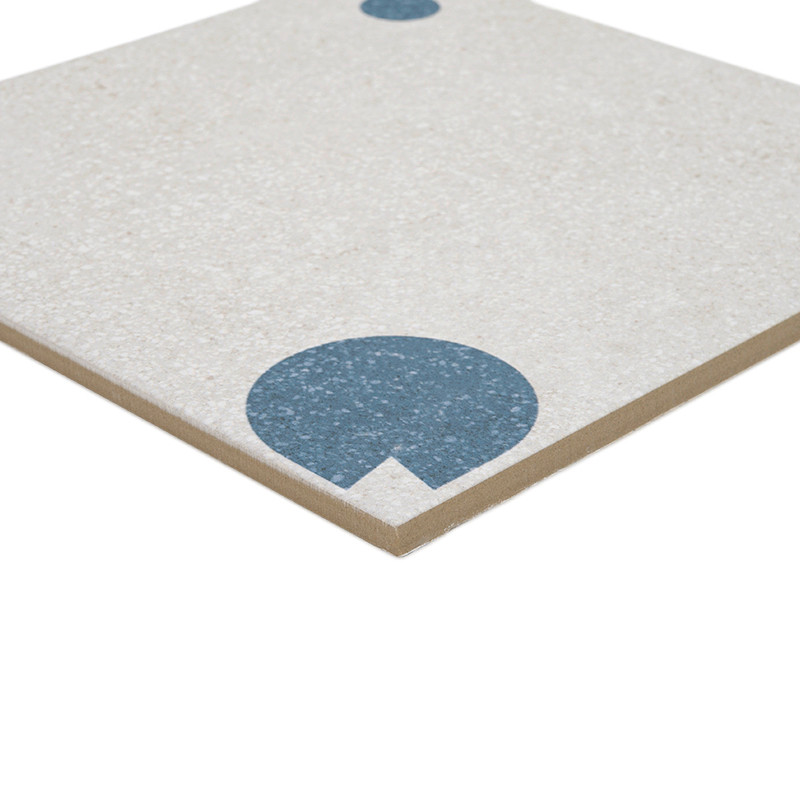 Eine beige quadratische Fliese weist einen großen blauen Halbkreis in der Nähe der Ecke und einen kleineren blauen Punkt am gege