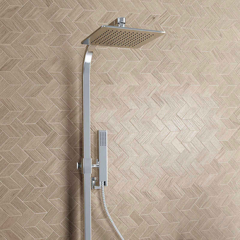 Um chuveiro elegante e moderno com um design quadrado se estende de uma luminária de aço inoxidável contra um fundo de ladrilho 